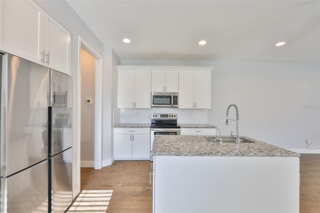 6619 S Manhattan Ave Unit 1, Tampa, FL 33616 - kitchen with appliances with stainless steel finishes, a sink, light wood-style floors, decorative backsplash, and white cabinetry
