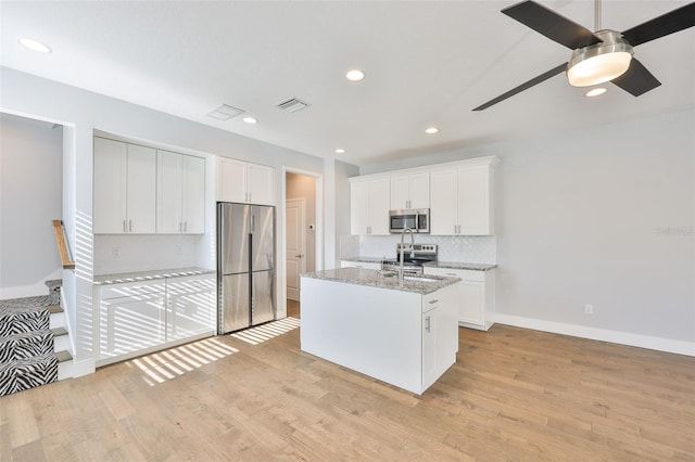 6619 S Manhattan Ave Unit 1, Tampa, FL 33616 - kitchen featuring appliances with stainless steel finishes, light wood-style flooring, a kitchen island with sink, white cabinets, and recessed lighting
