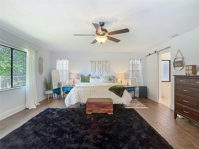 1014 Sylvia Ln, Tampa, FL 33613 - bedroom featuring a barn door, wood finished floors, a ceiling fan, and ensuite bathroom