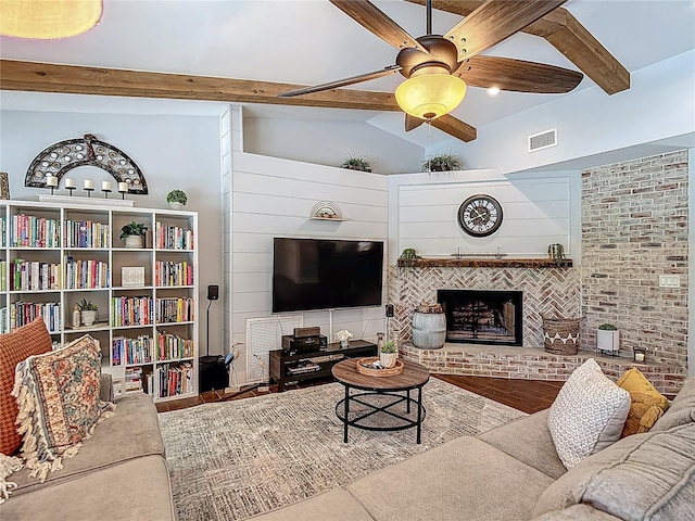 1014 Sylvia Ln, Tampa, FL 33613 - living area with wood finished floors, a ceiling fan, a brick fireplace, and beamed ceiling