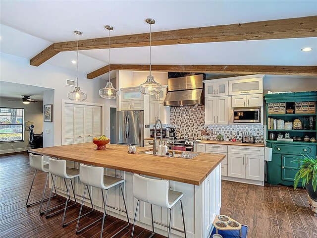 1014 Sylvia Ln, Tampa, FL 33613 - kitchen with butcher block countertops, appliances with stainless steel finishes, wall chimney range hood, white cabinetry, and tasteful backsplash
