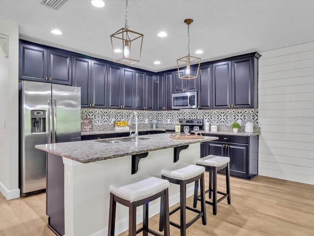 12428 Chaya Ct, Spring Hill, FL 34610 - kitchen with stainless steel appliances, a sink, light stone counters, light wood finished floors, and a kitchen bar