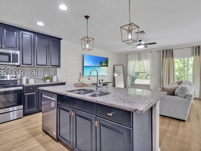 12428 Chaya Ct, Spring Hill, FL 34610 - kitchen with stainless steel appliances, a sink, open floor plan, light wood finished floors, and light stone counters