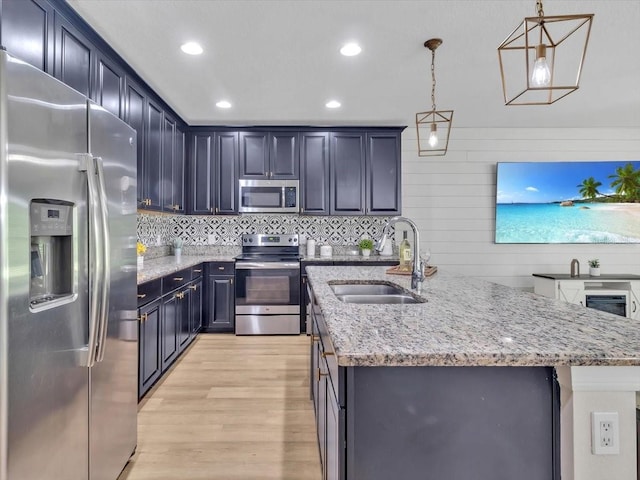 12428 Chaya Ct, Spring Hill, FL 34610 - kitchen featuring stainless steel appliances, a sink, light wood finished floors, a center island with sink, and light stone countertops