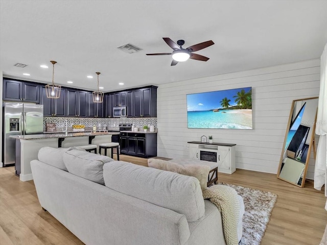 12428 Chaya Ct, Spring Hill, FL 34610 - living room with ceiling fan, light wood-style floors, wooden walls, and recessed lighting