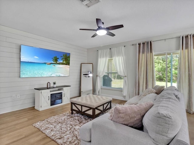 12428 Chaya Ct, Spring Hill, FL 34610 - living room with wooden walls, a ceiling fan, light wood finished floors, and baseboards