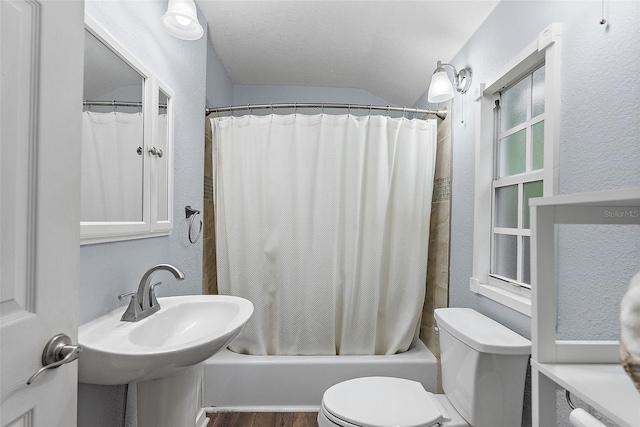 1211 14th St N, Saint Petersburg, FL 33705 - bathroom featuring toilet, shower / tub combo, lofted ceiling, a textured wall, and wood finished floors