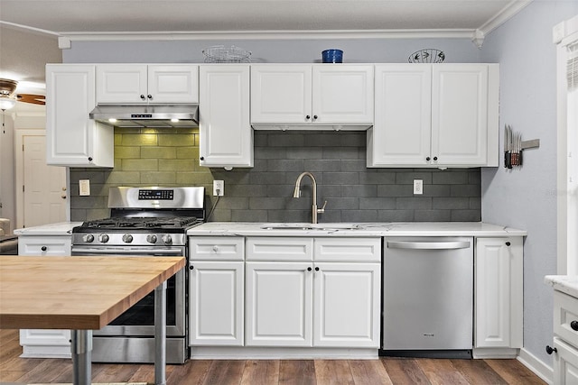 1211 14th St N, Saint Petersburg, FL 33705 - kitchen featuring stainless steel appliances, under cabinet range hood, a sink, crown molding, and white cabinets