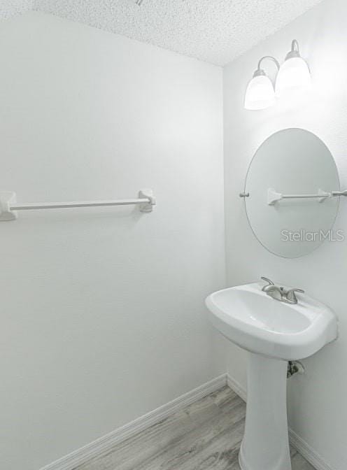 6229 Bayside Key Dr, Tampa, FL 33615 - bathroom with a textured ceiling, wood finished floors, baseboards, and a sink