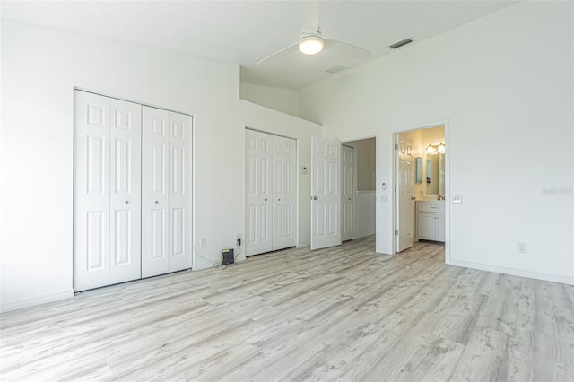 6229 Bayside Key Dr, Tampa, FL 33615 - unfurnished bedroom featuring two closets, light wood-style flooring, vaulted ceiling, ensuite bathroom, and baseboards