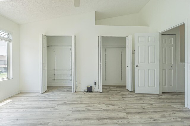 6229 Bayside Key Dr, Tampa, FL 33615 - unfurnished bedroom with two closets, light wood-style flooring, vaulted ceiling, a textured ceiling, and a ceiling fan