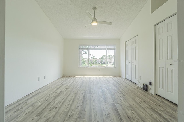 6229 Bayside Key Dr, Tampa, FL 33615 - unfurnished bedroom featuring light wood finished floors, a textured ceiling, multiple closets, ceiling fan, and vaulted ceiling