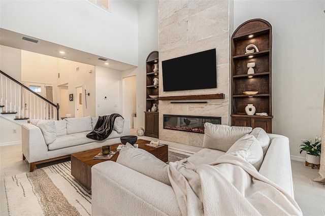 33774 Castaway Loop, Wesley Chapel, FL 33543 - living room featuring built in shelves, baseboards, a glass covered fireplace, stairway, and a high ceiling