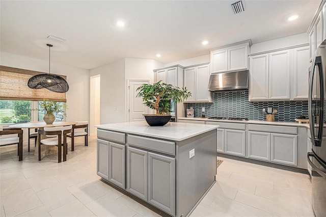 33774 Castaway Loop, Wesley Chapel, FL 33543 - kitchen featuring gray cabinetry, under cabinet range hood, stainless steel gas cooktop, backsplash, and light countertops