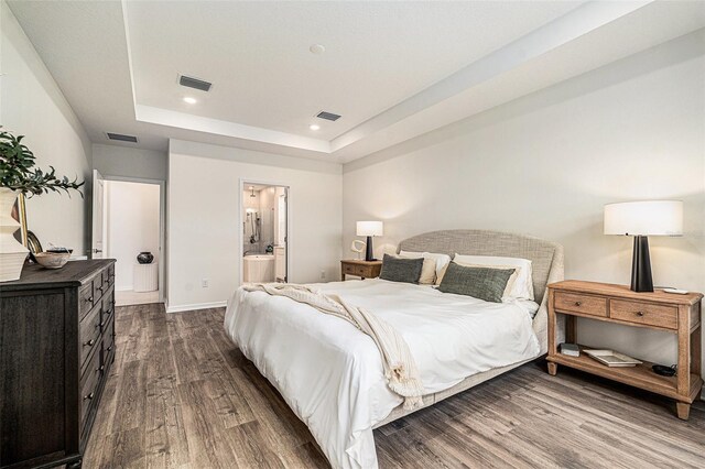 33774 Castaway Loop, Wesley Chapel, FL 33543 - bedroom with dark wood-style floors, a tray ceiling, baseboards, recessed lighting, and ensuite bath
