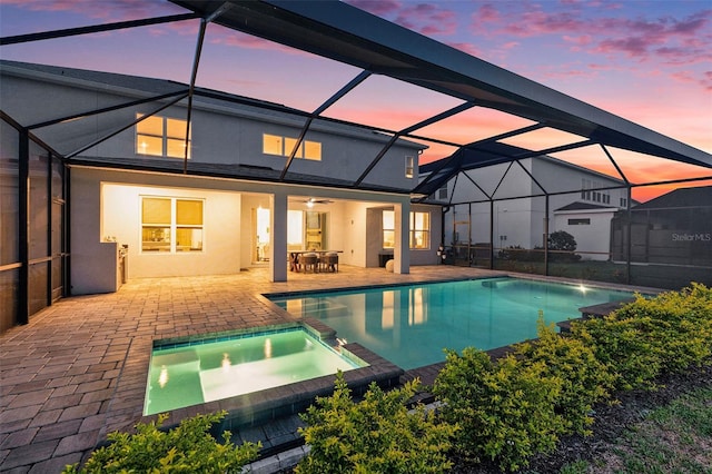 33774 Castaway Loop, Wesley Chapel, FL 33543 - back of property at dusk featuring a patio area, stucco siding, a pool with connected hot tub, a ceiling fan, and a lanai