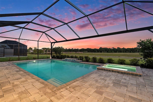 33774 Castaway Loop, Wesley Chapel, FL 33543 - pool at dusk featuring a patio area, glass enclosure, and a pool with connected hot tub