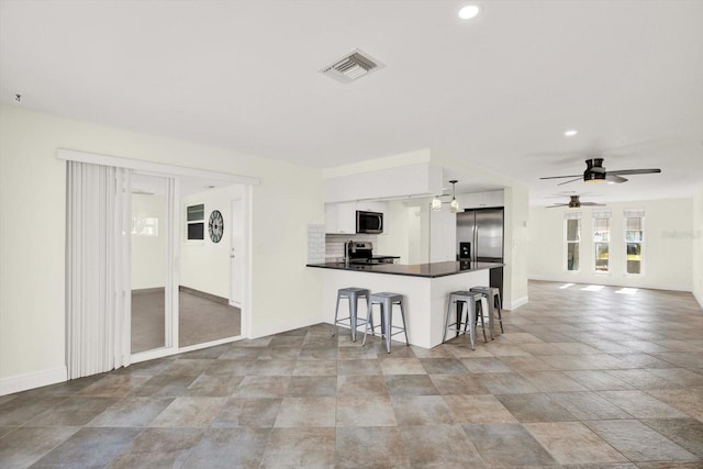 13926 Darlene Ave, Hudson, FL 34667 - kitchen with appliances with stainless steel finishes, ceiling fan, a peninsula, a breakfast bar area, and white cabinetry