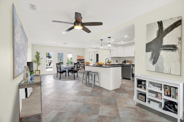 13926 Darlene Ave, Hudson, FL 34667 - kitchen with dark countertops, recessed lighting, a breakfast bar area, ceiling fan, and white cabinets