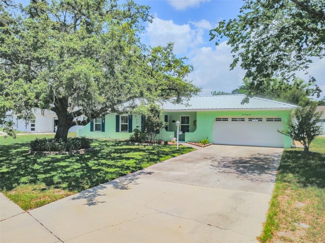 1022 Greenbriar Dr, Brandon, FL 33511 - view of front facade featuring an attached garage, concrete driveway, a front yard, stucco siding, and metal roof