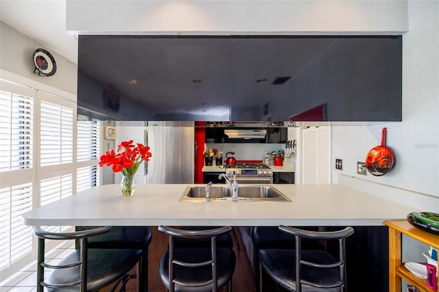 1022 Greenbriar Dr, Brandon, FL 33511 - kitchen featuring a sink, under cabinet range hood, light countertops, a peninsula, and a breakfast bar