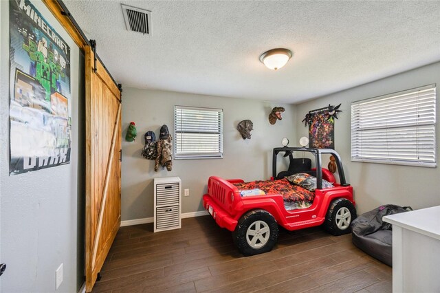 3217 Mott Rd, Dover, FL 33527 - bedroom with a barn door, wood finished floors, a textured ceiling, and baseboards