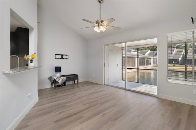 500 New York Ave Unit 23, Dunedin, FL 34698 - empty room featuring light wood-style floors, a ceiling fan, baseboards, and high vaulted ceiling