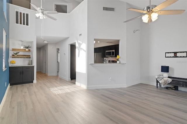 500 New York Ave Unit 23, Dunedin, FL 34698 - unfurnished living room with a ceiling fan, a high ceiling, light wood-type flooring, and baseboards