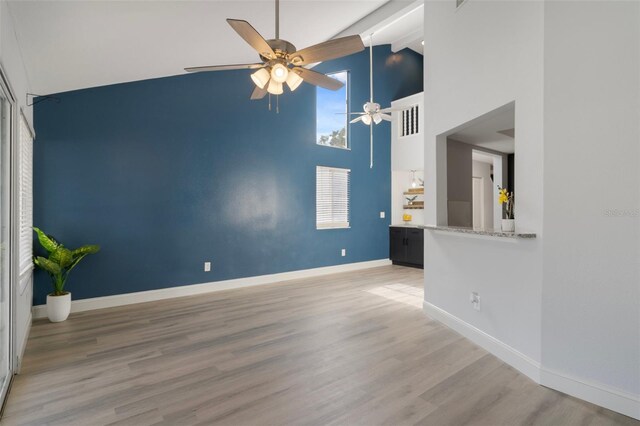 500 New York Ave Unit 23, Dunedin, FL 34698 - unfurnished living room featuring high vaulted ceiling, ceiling fan, wood finished floors, and baseboards