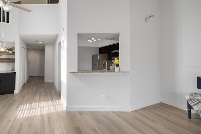 500 New York Ave Unit 23, Dunedin, FL 34698 - unfurnished living room featuring light wood-type flooring, a high ceiling, baseboards, and ceiling fan