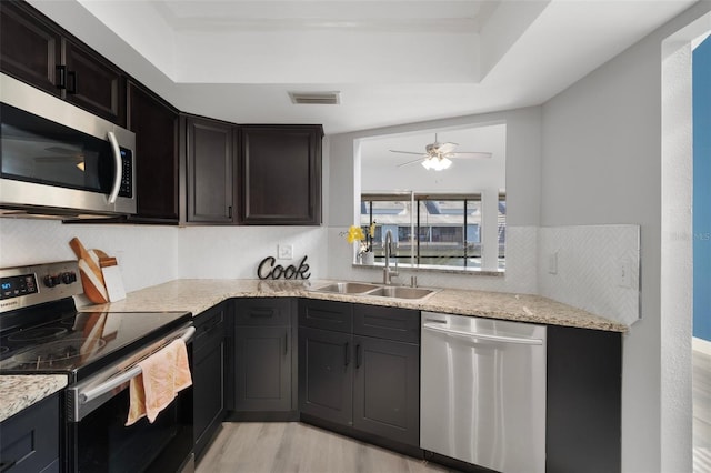 500 New York Ave Unit 23, Dunedin, FL 34698 - kitchen with appliances with stainless steel finishes, a sink, light wood-style flooring, and light stone countertops