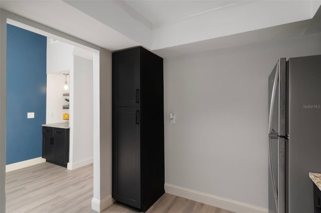 500 New York Ave Unit 23, Dunedin, FL 34698 - kitchen with freestanding refrigerator, light wood-type flooring, baseboards, light stone countertops, and dark cabinets