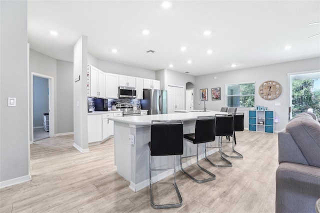 229 St Thomas Dr, Mulberry, FL 33860 - kitchen featuring appliances with stainless steel finishes, open floor plan, a center island with sink, white cabinets, and light countertops