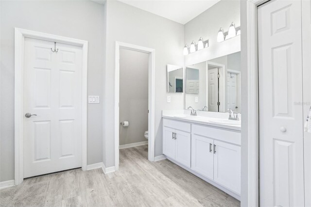 229 St Thomas Dr, Mulberry, FL 33860 - bathroom featuring double vanity, wood finished floors, toilet, and baseboards