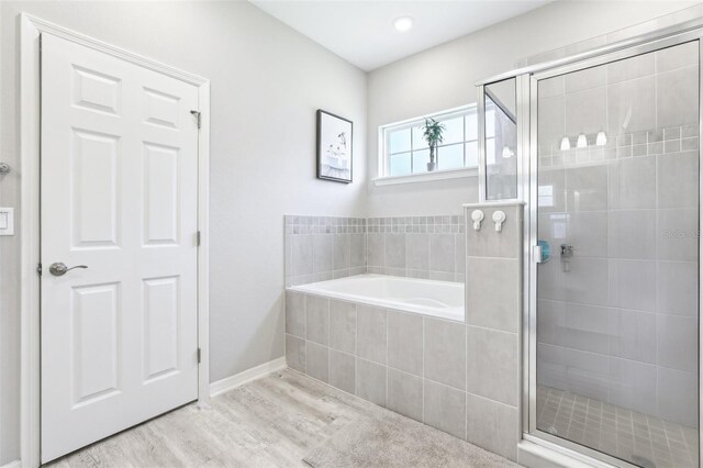 229 St Thomas Dr, Mulberry, FL 33860 - full bathroom featuring wood finished floors, a garden tub, a stall shower, and baseboards