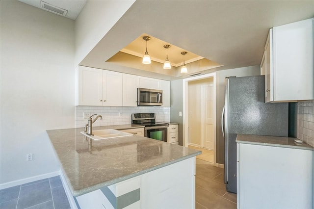 2204 78th St W, Bradenton, FL 34209 - kitchen featuring appliances with stainless steel finishes, a sink, a peninsula, a tray ceiling, and white cabinetry