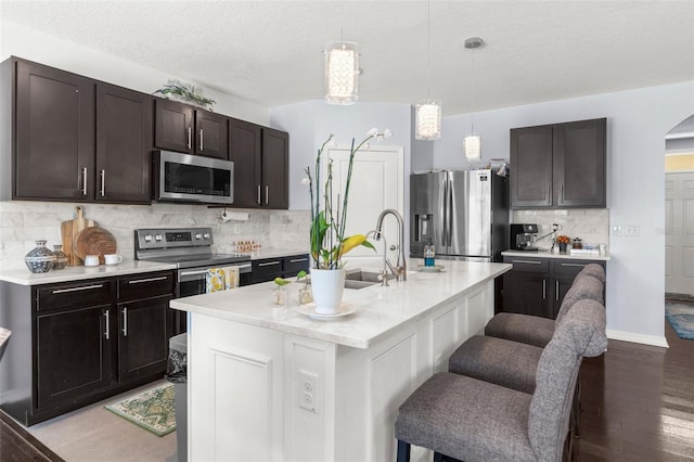 30936 Summer Sun Loop, Wesley Chapel, FL 33545 - kitchen with appliances with stainless steel finishes, decorative backsplash, light countertops, a breakfast bar, and pendant lighting