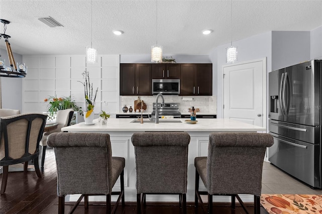 30936 Summer Sun Loop, Wesley Chapel, FL 33545 - kitchen with stainless steel appliances, a sink, light countertops, a textured ceiling, and decorative backsplash