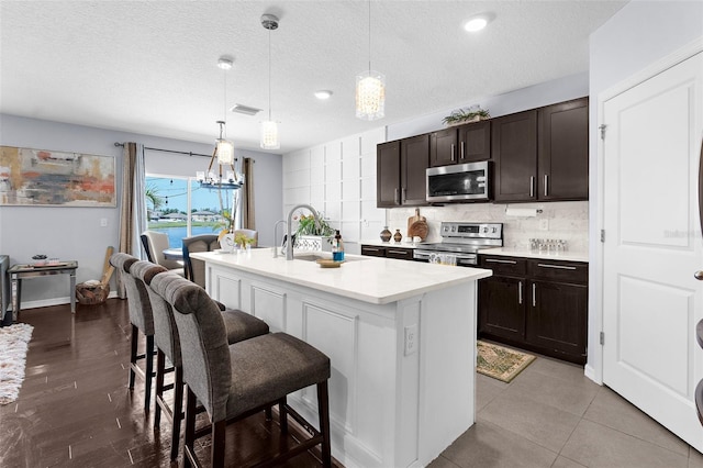 30936 Summer Sun Loop, Wesley Chapel, FL 33545 - kitchen with stainless steel appliances, a sink, light countertops, a breakfast bar, and a center island with sink