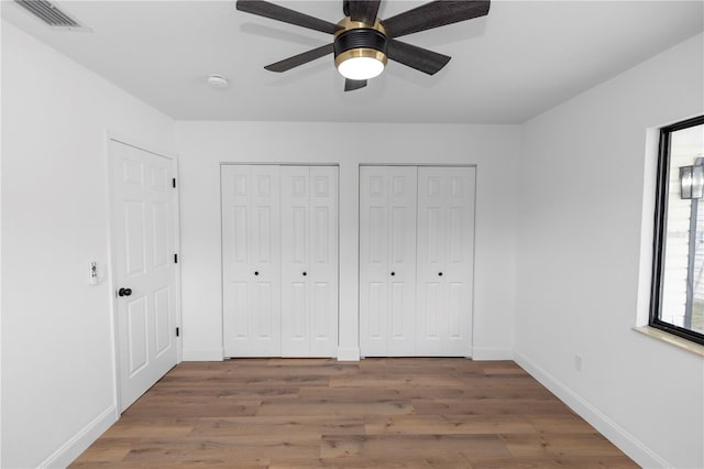 1161 Orangewood Ave, Deland, FL 32724 - unfurnished bedroom with two closets, wood finished floors, baseboards, and ceiling fan