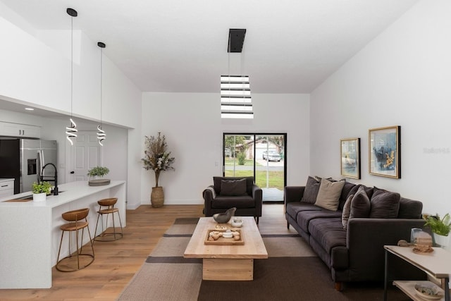 1161 Orangewood Ave, Deland, FL 32724 - living room featuring light wood-type flooring, a towering ceiling, and baseboards