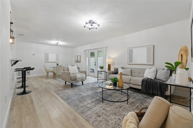 1470 Serpentine Dr S, Saint Petersburg, FL 33705 - living room with light wood-type flooring, french doors, a textured ceiling, and baseboards