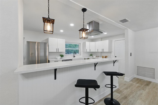 1470 Serpentine Dr S, Saint Petersburg, FL 33705 - kitchen featuring freestanding refrigerator, island exhaust hood, a breakfast bar, white cabinetry, and light countertops