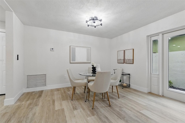 1470 Serpentine Dr S, Saint Petersburg, FL 33705 - dining room featuring light wood-style flooring, a textured ceiling, and baseboards