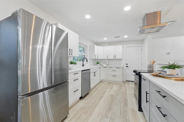 1470 Serpentine Dr S, Saint Petersburg, FL 33705 - kitchen featuring stainless steel appliances, ventilation hood, light wood-type flooring, white cabinetry, and light countertops