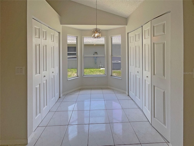 8812 Bayaud Dr, Tampa, FL 33626 - interior space featuring vaulted ceiling, a chandelier, a textured ceiling, light tile patterned floors, and baseboards