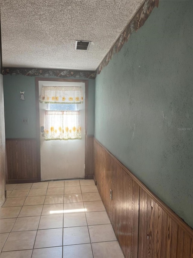 2220 Woods Trl, Lakeland, FL 33809 - empty room featuring wainscoting, wooden walls, a textured ceiling, and light tile patterned floors