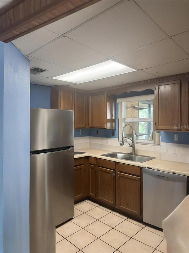 2220 Woods Trl, Lakeland, FL 33809 - kitchen featuring stainless steel appliances, a sink, light countertops, light tile patterned floors, and a drop ceiling