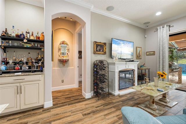 12672 Fontana Loop, Bradenton, FL 34211 - living area featuring arched walkways, bar, wood finished floors, ornamental molding, and a glass covered fireplace