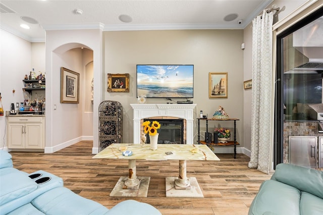 12672 Fontana Loop, Bradenton, FL 34211 - living room with arched walkways, light wood-style floors, ornamental molding, baseboards, and a glass covered fireplace